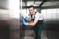 handsome young cleaning company worker cleaning elevator and smiling