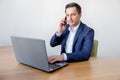 Handsome young concentrated attractive man using cellphone while working with laptop in the office Royalty Free Stock Photo