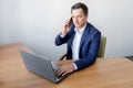 Handsome young concentrated attractive man using cellphone while working with laptop in the office Royalty Free Stock Photo