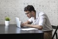 Handsome young businessman freelancer working on laptop at the desk in the living room. Distant work from home concept Royalty Free Stock Photo