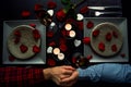 Handsome young couple having romantic diner holding hands. Top view. Candles, flowers and wine