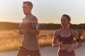 A handsome young couple running together during the early morning hours, with the mesmerizing sunrise casting a warm