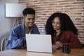 Handsome young couple using laptop together while sitting at home. Smiling friends looking at computer and laughing at Royalty Free Stock Photo