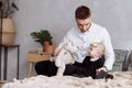 Handsome young dad and his cute baby girl are sitting and playing with teddy bear on bed at home. father`s, baby`s day. family Royalty Free Stock Photo