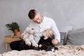 Handsome young dad and his cute baby girl are sitting and playing with teddy bear on bed at home. father`s, baby`s day. family Royalty Free Stock Photo