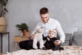 Handsome young dad and his cute baby girl are sitting and playing with teddy bear on bed at home. father`s, baby`s day. family Royalty Free Stock Photo