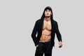 Handsome young dancer dressed in a sweatshirt on a naked torso with a hood on the cap and black pants stands with his Royalty Free Stock Photo