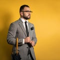 Handsome young English man wearing grey suit and eye glasses with one hand lifted standing with cane or umbrella in his Royalty Free Stock Photo