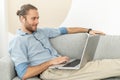 Young European man sitting on the sofa with laptop and earphones Royalty Free Stock Photo