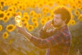 Handsome young farmer standing in the middle of a sunflower field talking on phone while holding up a sunflower oil bottle during Royalty Free Stock Photo