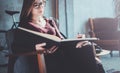 Handsome young girl wearing glasses casual clothes holding book hands.Woman blonde sitting in vintage armchair modern Royalty Free Stock Photo