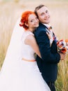 Handsome young groom and beautiful redhair bride posing outdoor, enjoying marriage day together Royalty Free Stock Photo