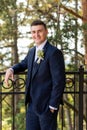 Handsome young groom wearing elegant and stylish dark blue suit outdoors portrait. Happy groom looking and smiling at camera. Royalty Free Stock Photo