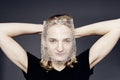 A handsome young guy with long blonde hair and sad blue eyes holds a bubble wrap in front of his face on a gray background Royalty Free Stock Photo