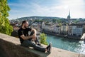 Handsome young guy sit in the city park with a city view in Zurich, Switzerland.