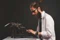 Handsome young hipster businessman thinking and writing with vintage typewriter. Royalty Free Stock Photo