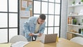 Handsome young hispanic man engrossed in reading business documents on laptop at office, hardworking and focused on success Royalty Free Stock Photo