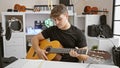 Handsome young hispanic man passionately playing classic guitar, serenading the room with his acoustic melody at music studio Royalty Free Stock Photo