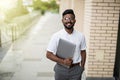 Handsome young indian hipster man holding his laptop while standing on the street near bussines office Royalty Free Stock Photo