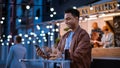 Handsome Young Indian Man is Using a Smartphone while Sitting at a Table in a Outdoors Street Food Royalty Free Stock Photo