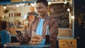 Handsome Young Indian Man is Using a Smartphone while Sitting at a Table in a Outdoors Street Food Royalty Free Stock Photo