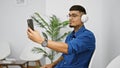 Handsome young latin man engrossed in a serious business video call conversation on his mobile, sitting in a chair in the waiting Royalty Free Stock Photo