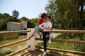 handsome young latin man and woman couple are in the forest on a wooden railing and look at each other lovingly and in love. Royalty Free Stock Photo