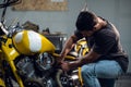 A handsome young male biker in his garage is preparing his motorcycle for the season. Repair and tuning. Royalty Free Stock Photo