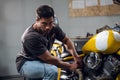 A handsome young male biker in his garage is preparing his motorcycle for the season. Repair and tuning. Royalty Free Stock Photo