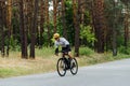 Handsome young male cyclist trains outside the city in the woods on the road. Riding a bike Royalty Free Stock Photo