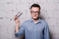 Handsome young male hairdresser in glasses, posing with scissors and comb, on gray brick wall background, horizontal Royalty Free Stock Photo