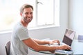 Handsome young male student smiling at camera seated behind laptop Royalty Free Stock Photo