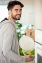 handsome young male vegan smiling excitedly holding fresh green lettuce