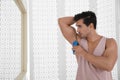 Handsome young man applying deodorant in bathroom Royalty Free Stock Photo