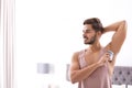 Handsome young man applying deodorant in bedroom Royalty Free Stock Photo