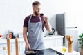 handsome young man in apron drinking red wine while cooking steak Royalty Free Stock Photo