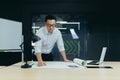 An Asian man architect, designer, engineer stands in the office, works with plans, documents Royalty Free Stock Photo