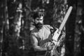 Handsome young man with axe near forest. Deforestation. Lumberjack in the woods with chainsaw axe. Agriculture and Royalty Free Stock Photo