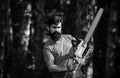 Handsome young man with axe near forest. Deforestation. Lumberjack in the woods with chainsaw axe. Agriculture and Royalty Free Stock Photo