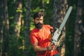 Handsome young man with axe near forest. Deforestation. Lumberjack in the woods with chainsaw axe. Agriculture and Royalty Free Stock Photo
