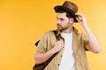 handsome young man with backpack adjusting hat and looking away Royalty Free Stock Photo