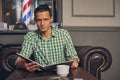 Handsome young man in a barbershop is waiting for the master in the waiting room while drinking coffee