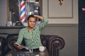 Handsome young man in a barbershop is waiting for the master in the waiting room while drinking coffee