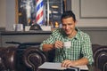 Handsome young man in a barbershop is waiting for the master in the waiting room while drinking coffee