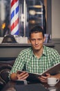 Handsome young man in a barbershop is waiting for the master in the waiting room while drinking coffee