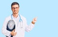 Handsome young man with bear as nutritionist doctor holding weighing machine smiling happy pointing with hand and finger to the