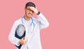 Handsome young man with bear as nutritionist doctor holding weighing machine stressed and frustrated with hand on head, surprised