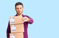 Handsome young man with bear holding delivery packages with angry face, negative sign showing dislike with thumbs down, rejection Royalty Free Stock Photo