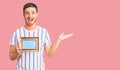 Handsome young man with bear holding empty frame celebrating victory with happy smile and winner expression with raised hands Royalty Free Stock Photo