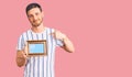 Handsome young man with bear holding empty frame pointing finger to one self smiling happy and proud Royalty Free Stock Photo